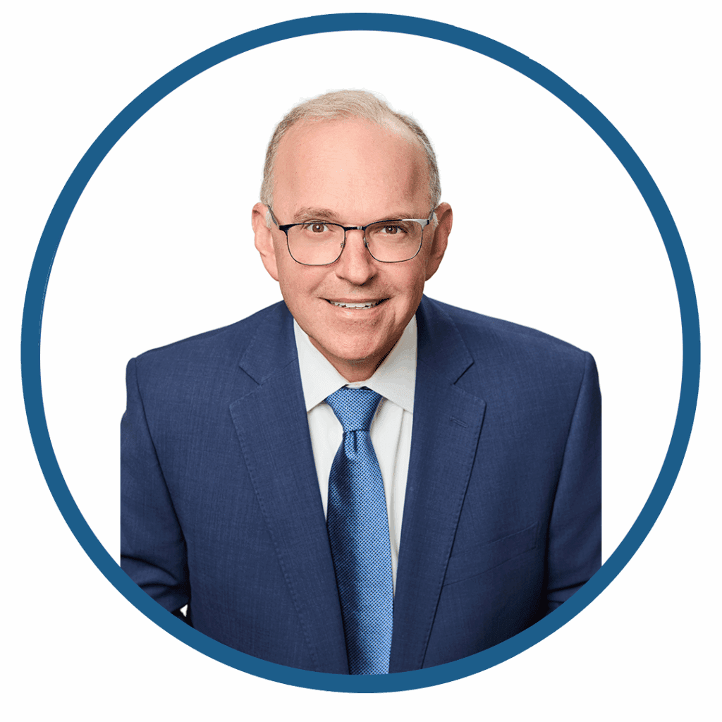Man in blue suit and glasses smiling.