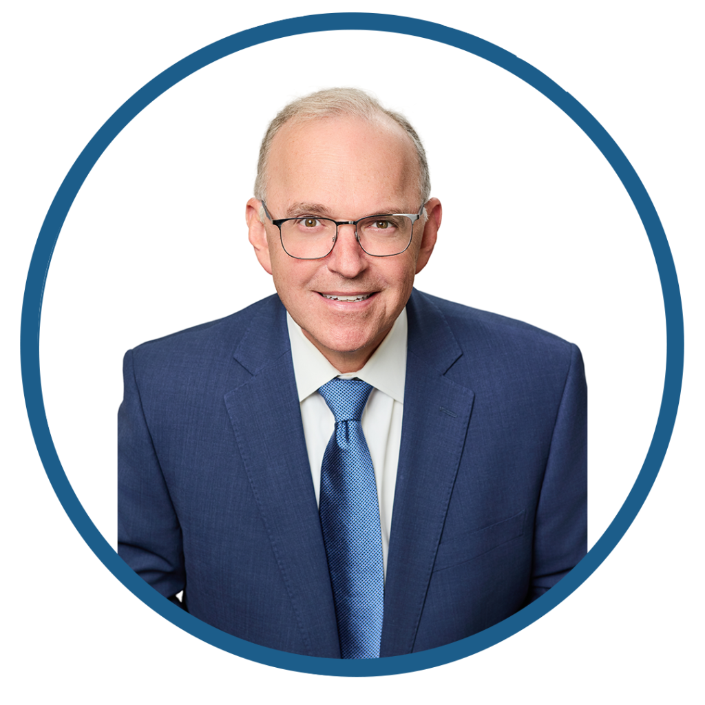 Professional headshot of an elderly man in a blue suit and tie.