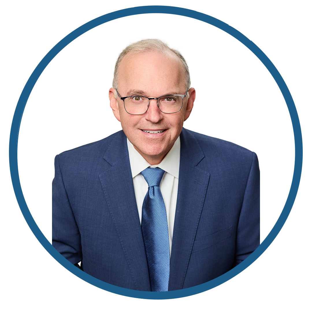 Professional headshot of an elderly man in a blue suit and tie.