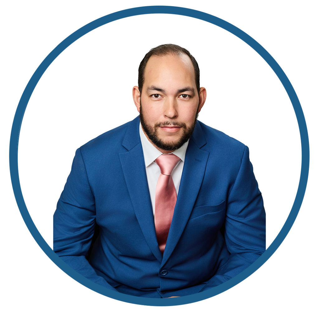 Professional man in blue suit and pink tie posing for a headshot.