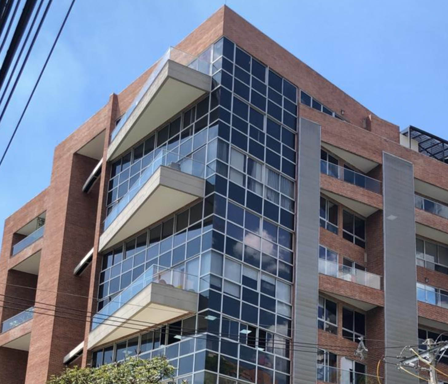 Modern apartment building with glass balconies and brick exterior.